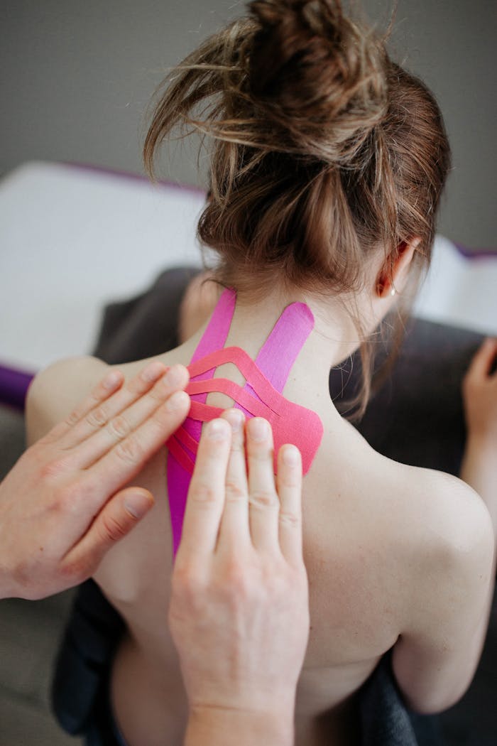 our-services-3 Close-up of hands applying kinesio tape on a woman's neck for pain relief.